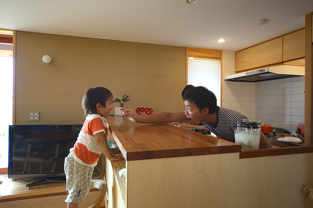 姫路市の木の家 対面キッチン越しに触れ合うご主人とお子さん